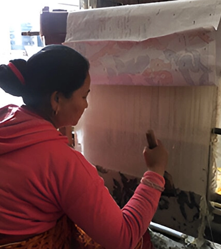 A woman in red jacket painting on wall.