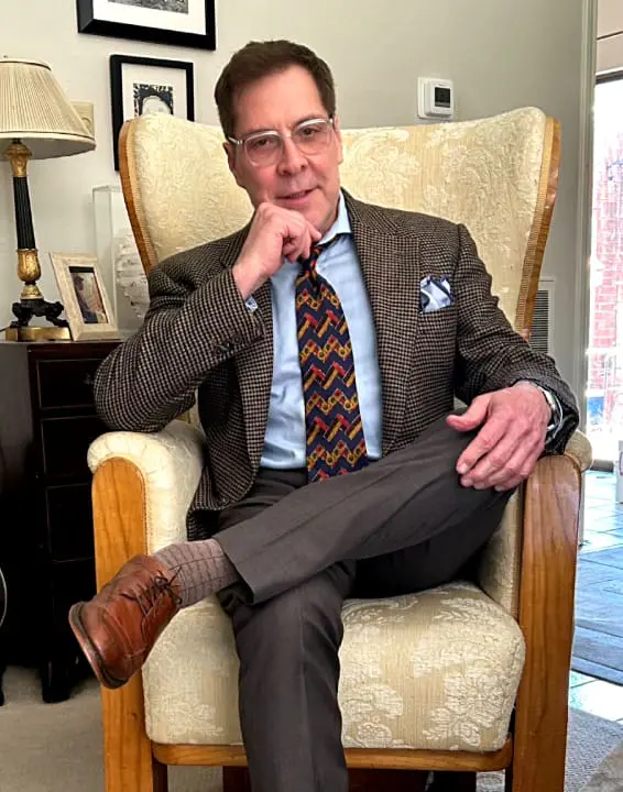 A man sitting in a chair wearing a suit and tie.