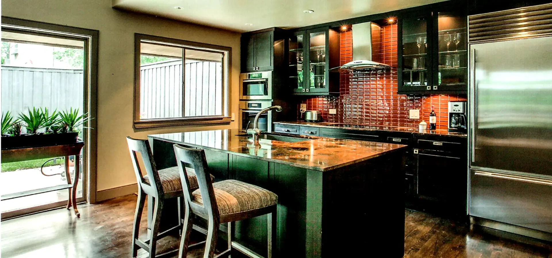 A kitchen with green cabinets and brown tile.