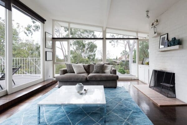 A living room with large windows and blue rug.