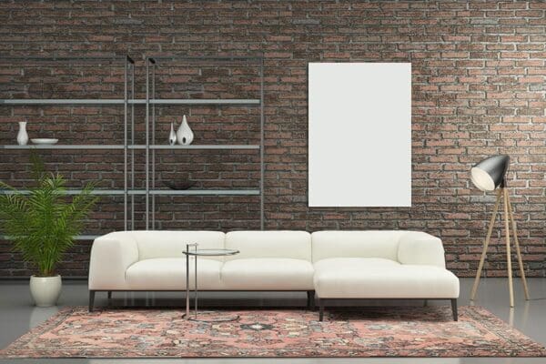 A white couch sitting in front of a brick wall.