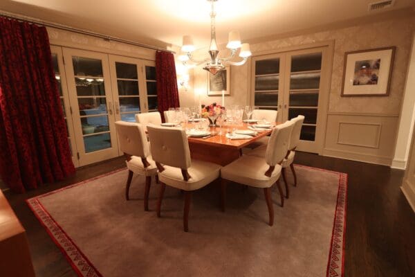 A dining room table with six chairs and a chandelier.