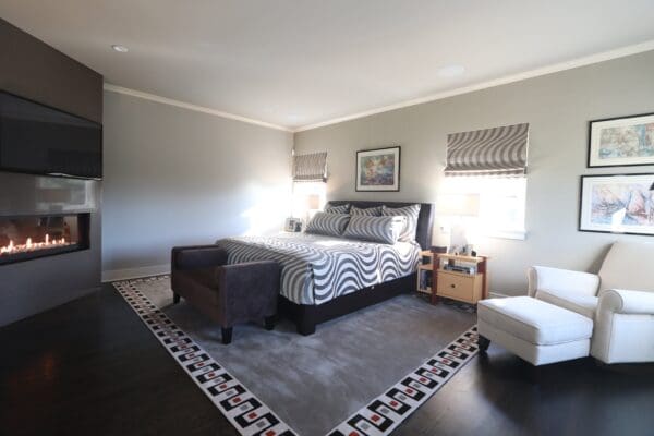 A bedroom with a bed, ottoman and rug.